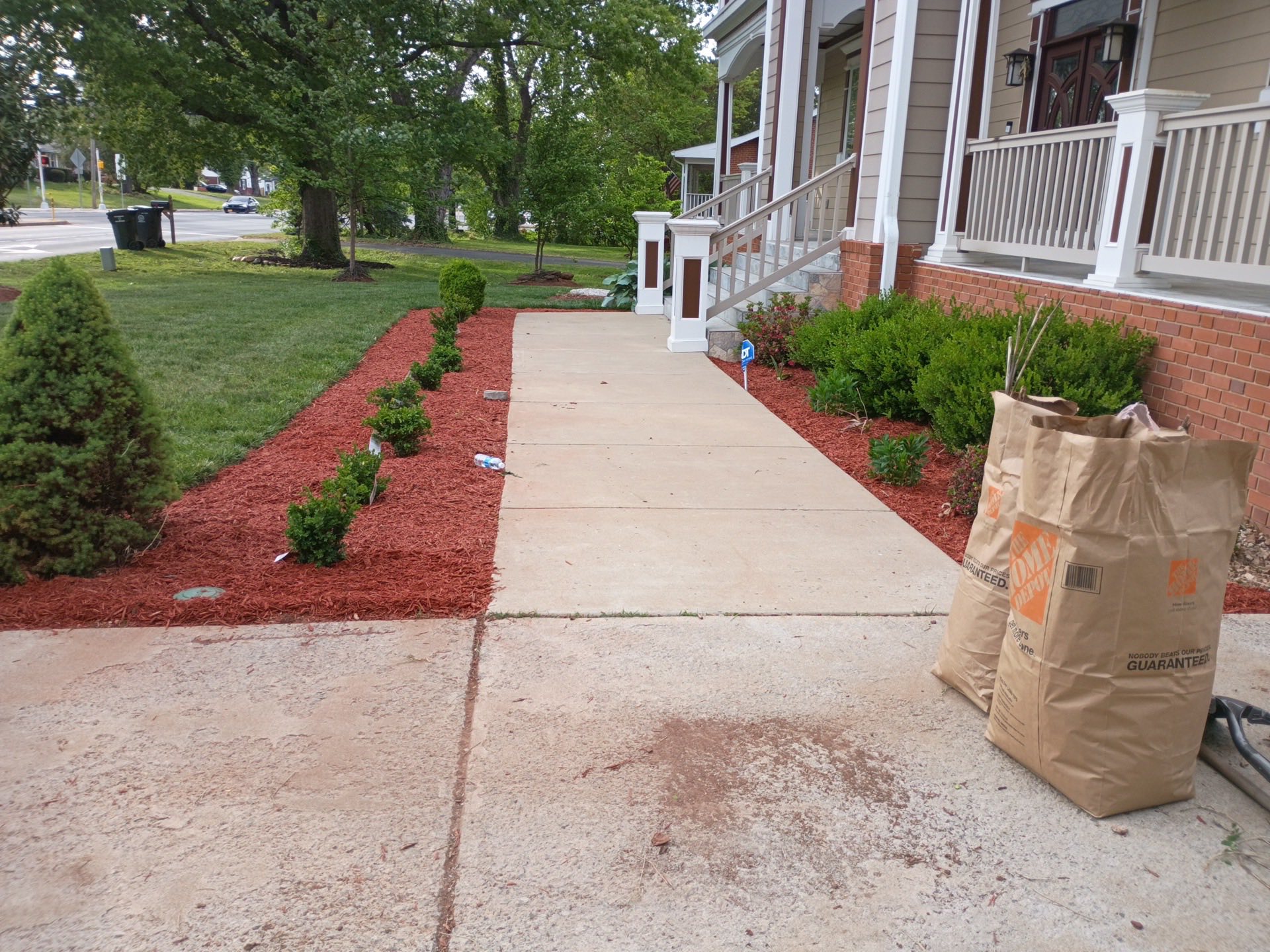 Freshly landscaped front yard with red mulch beds, shrubs, and a clean walkway
