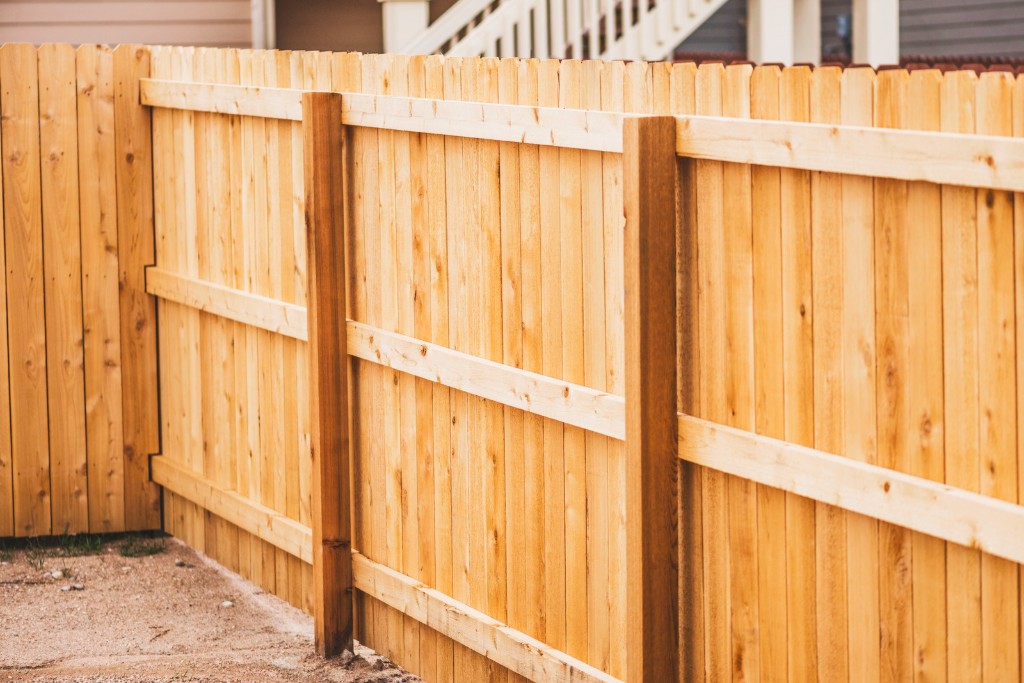 Newly installed natural wood privacy fence with dog-ear pickets and horizontal rails